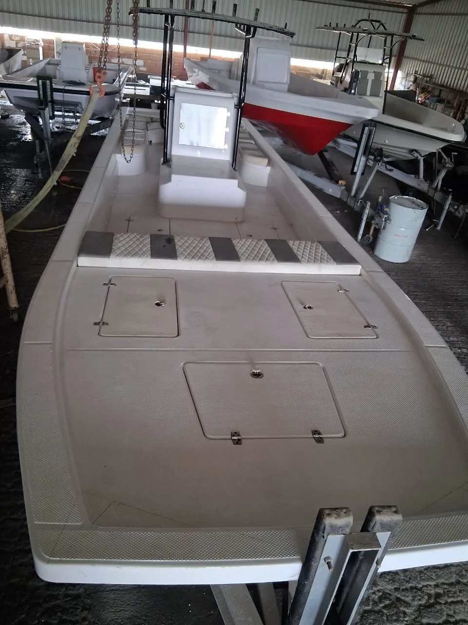 A long fiberglass deck under construction in the Almarri workshop, more hulls in progress behind it