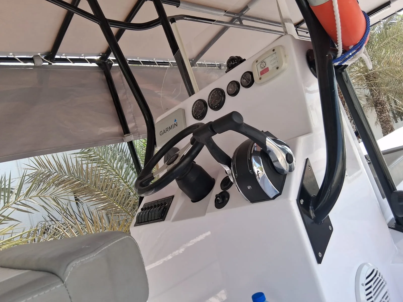A helm console with Garmin navigation, gauges, and twin-engine controls under a shade top